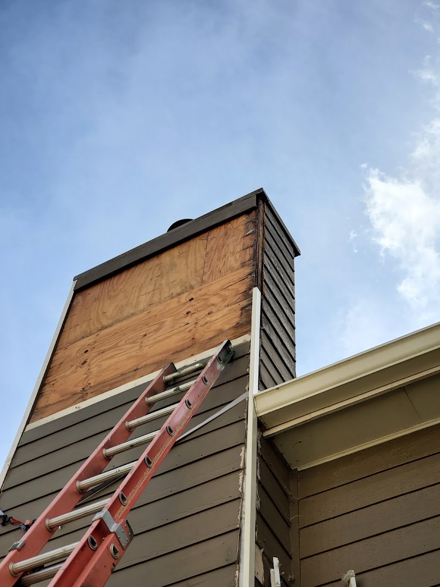 Deck and porch framing in progress beside a hillside home, with the crew building the outdoor structure.